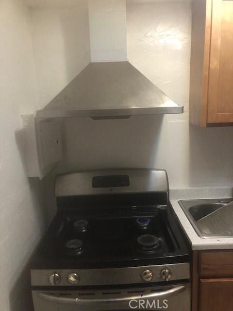 1505 Victoria Dr, Modesto, CA 95351 - kitchen view of electric stove, wall chimney exhaust hood, light countertops, brown cabinetry, and a sink
