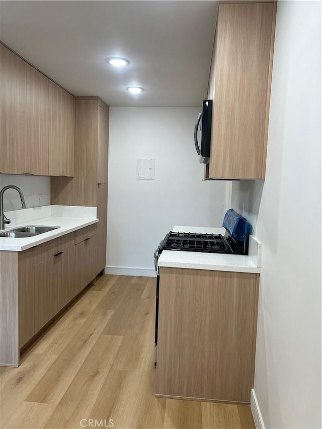 14805 Chase St Unit 224, Panorama City, CA 91402 - kitchen with a sink, light countertops, light wood-style flooring, and black microwave