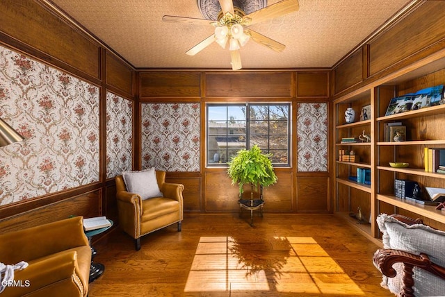 10484 Creek Rd, Oak View, CA 93022 - sitting room featuring wood finished floors, a ceiling fan, a wainscoted wall, wooden walls, and wallpapered walls
