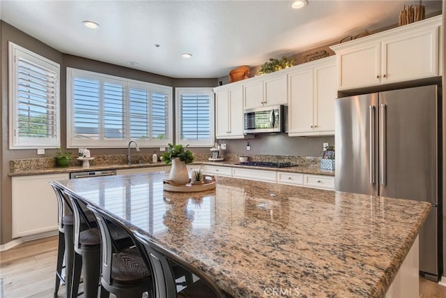 4765 Falconview Ct, Fontana, CA 92336 - kitchen featuring stainless steel appliances, light stone countertops, white cabinetry, a breakfast bar, and recessed lighting