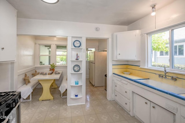 1139 N Heliotrope Dr, Los Angeles, CA 90029 - kitchen with freestanding refrigerator, a sink, white cabinetry, open shelves, and light countertops