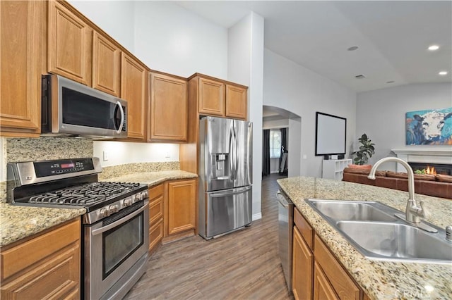 6662 W W Ave L4, Lancaster, CA 93536 - kitchen featuring appliances with stainless steel finishes, a sink, arched walkways, light wood finished floors, and brown cabinets