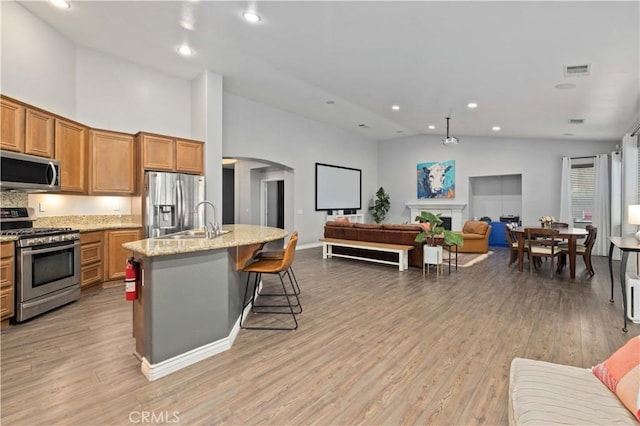 6662 W W Ave L4, Lancaster, CA 93536 - kitchen featuring appliances with stainless steel finishes, a sink, open floor plan, brown cabinets, and high vaulted ceiling