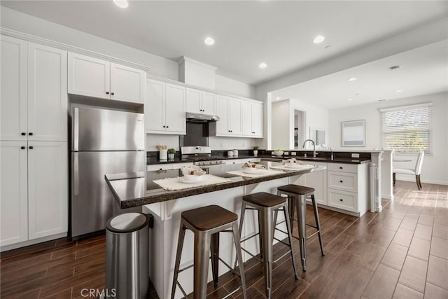 144 Borrego, Irvine, CA 92618 - kitchen with appliances with stainless steel finishes, dark wood finished floors, a peninsula, white cabinetry, and under cabinet range hood