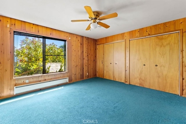 125 Cedar Gulch Rd, Hayfork, CA 96041 - unfurnished bedroom featuring a baseboard radiator, carpet flooring, wood walls, multiple closets, and ceiling fan