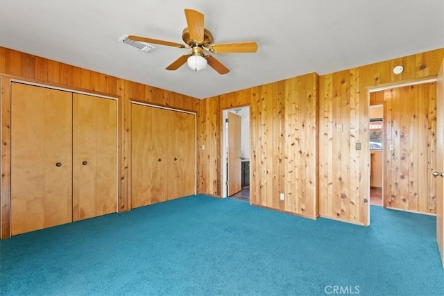 125 Cedar Gulch Rd, Hayfork, CA 96041 - unfurnished bedroom featuring carpet flooring, two closets, wooden walls, and ceiling fan