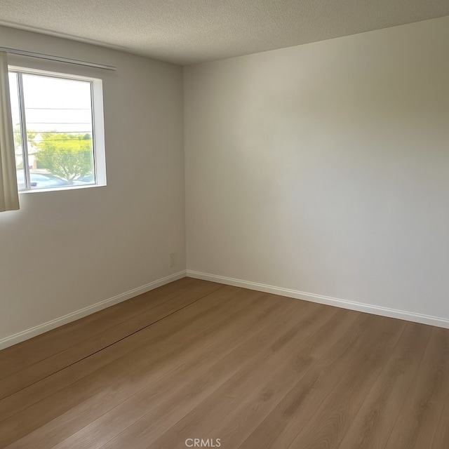 12905 Palm St, Garden Grove, CA 92840 - spare room featuring light wood-style flooring, baseboards, and a textured ceiling