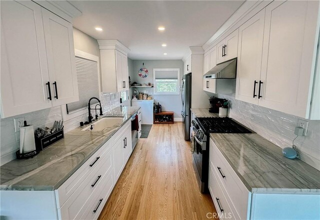 11304 Oklahoma Ave, South Gate, CA 90280 - kitchen featuring range with gas cooktop, under cabinet range hood, freestanding refrigerator, light wood finished floors, and tasteful backsplash