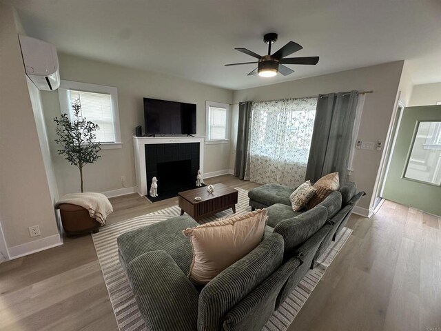 2453 Curlew St, San Diego, CA 92101 - living room featuring a wall unit AC, a fireplace, light wood-style flooring, a ceiling fan, and baseboards
