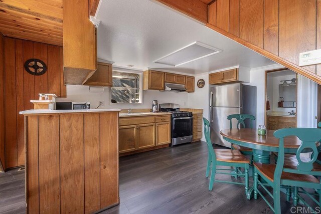 31450 Oceanview Dr, Running Springs, CA 92382 - kitchen with stainless steel appliances, ventilation hood, brown cabinetry, and dark wood-style flooring