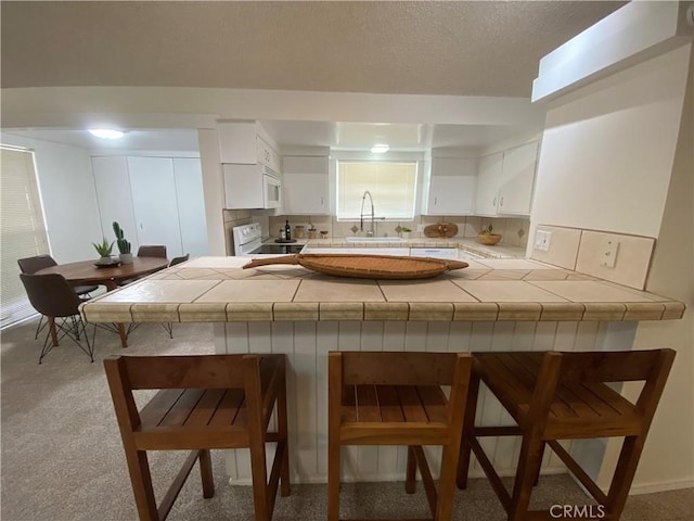 54858 Martinez Trl, Yucca Valley, CA 92284 - kitchen with white appliances, tile counters, a kitchen bar, and a peninsula