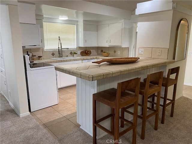 54858 Martinez Trl, Yucca Valley, CA 92284 - kitchen with white range, a kitchen bar, a peninsula, and white cabinetry