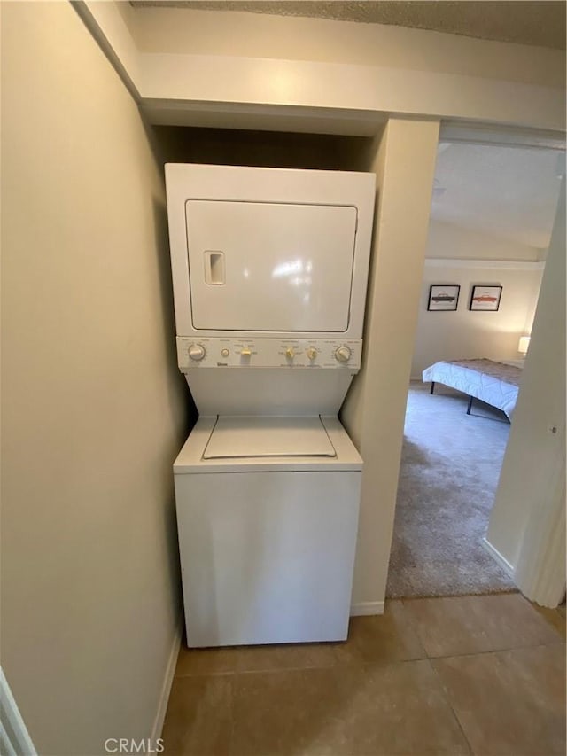 54858 Martinez Trl, Yucca Valley, CA 92284 - washroom featuring stacked washer and clothes dryer, tile patterned flooring, and carpet flooring