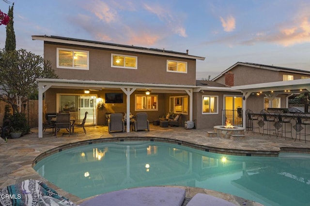 1099 N Agusta Ave, Camarillo, CA 93010 - back of house at dusk featuring a patio, stucco siding, and an outdoor living space with a fire pit