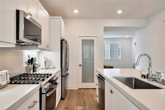 142 Juniper Dr, Rancho Mission Viejo, CA 92694 - kitchen featuring stainless steel appliances, a sink, light wood-style floors, light stone counters, and white cabinets