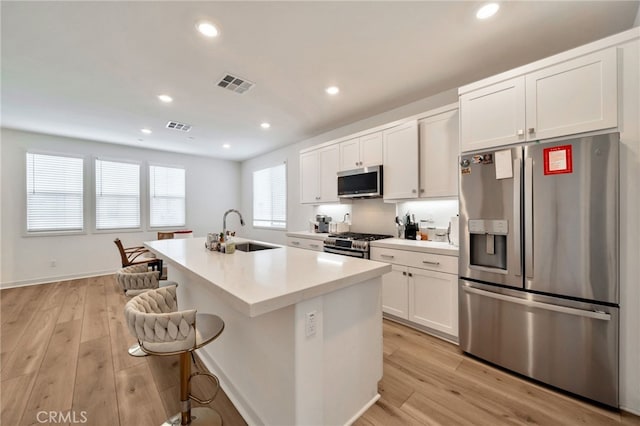142 Juniper Dr, Rancho Mission Viejo, CA 92694 - kitchen with appliances with stainless steel finishes, a sink, white cabinetry, an island with sink, and light wood-style flooring