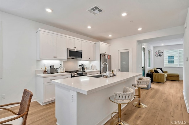 142 Juniper Dr, Rancho Mission Viejo, CA 92694 - kitchen featuring appliances with stainless steel finishes, a sink, a kitchen breakfast bar, light wood-style flooring, and an island with sink