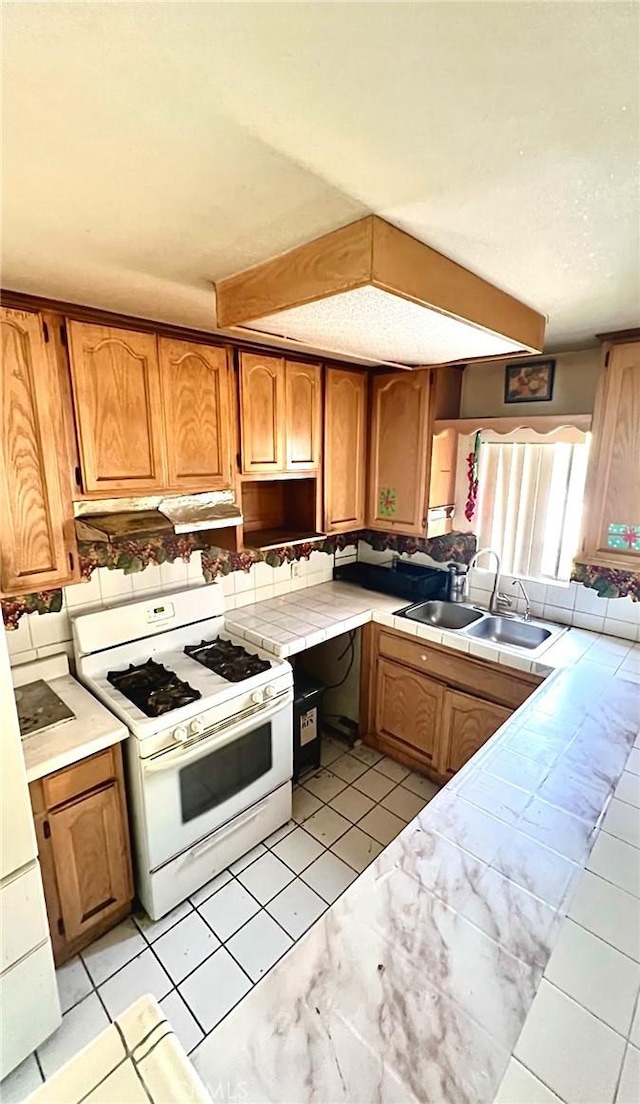 3748 W 118th St, Hawthorne, CA 90250 - kitchen with white range with gas cooktop, tile counters, under cabinet range hood, and brown cabinets