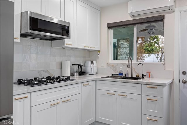 5911 Jones Ave, Westminster, CA 92683 - kitchen featuring stainless steel microwave, a wall mounted air conditioner, a sink, black gas stovetop, and white cabinetry