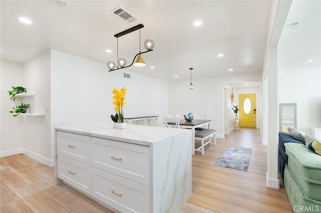 5911 Jones Ave, Westminster, CA 92683 - kitchen featuring light wood finished floors, white cabinetry, light stone counters, pendant lighting, and recessed lighting