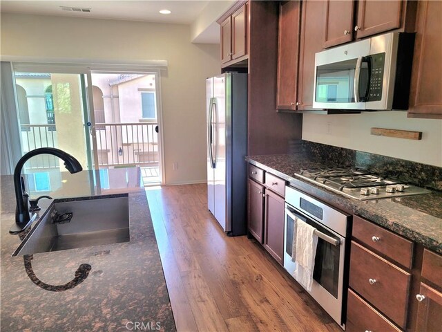 40955 Belleray Ave, Murrieta, CA 92562 - kitchen featuring appliances with stainless steel finishes, a sink, wood finished floors, dark stone counters, and recessed lighting