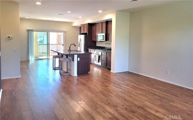 40955 Belleray Ave, Murrieta, CA 92562 - kitchen featuring white fridge with ice dispenser, dark countertops, stainless steel microwave, a sink, and a breakfast bar