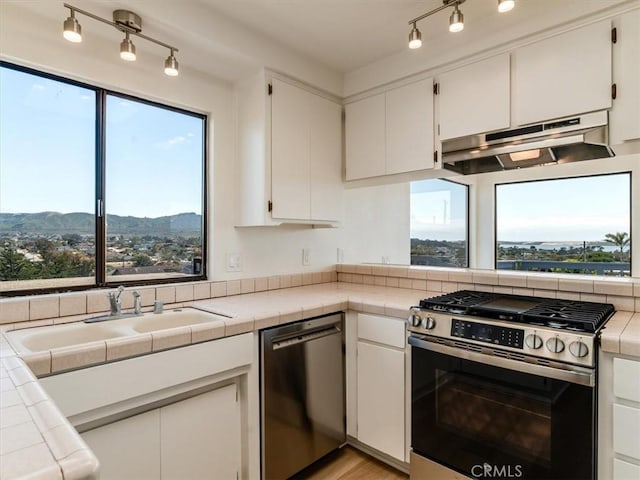 1311 15th St, Los Osos, CA 93402 - kitchen with stainless steel appliances, under cabinet range hood, white cabinets, and tile countertops