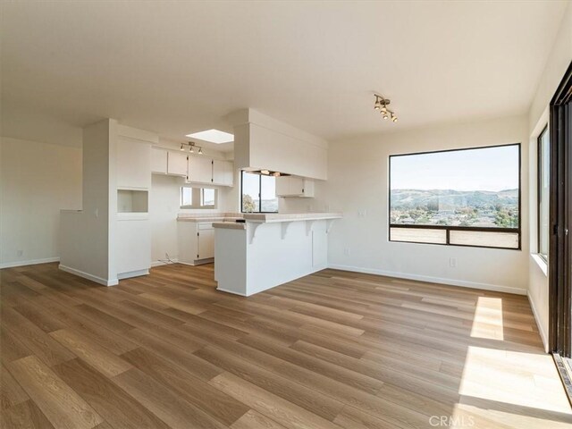 1311 15th St, Los Osos, CA 93402 - kitchen with a peninsula, white cabinets, light wood-type flooring, light countertops, and a kitchen bar