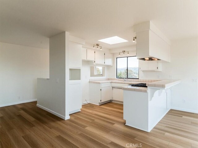 1311 15th St, Los Osos, CA 93402 - kitchen featuring a peninsula, light wood finished floors, tile counters, and white cabinets