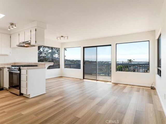 1311 15th St, Los Osos, CA 93402 - kitchen with gas range, under cabinet range hood, white cabinets, light wood-style floors, and open floor plan