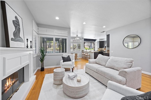 2300 Meadow View Ln, Chino Hills, CA 91709 - living room featuring a lit fireplace, light wood-type flooring, recessed lighting, a textured ceiling, and ceiling fan