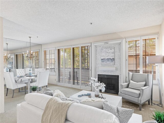 2563 Plaza Del Amo Unit 312, Torrance, CA 90503 - carpeted living room with a textured ceiling, a chandelier, a fireplace, and healthy amount of natural light