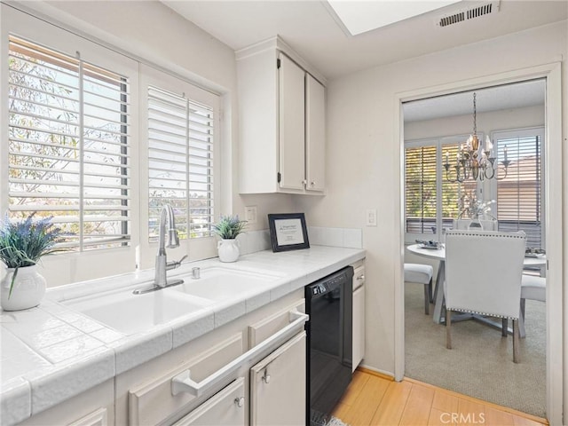 2563 Plaza Del Amo Unit 312, Torrance, CA 90503 - kitchen featuring black dishwasher, a sink, tile counters, light wood finished floors, and a chandelier