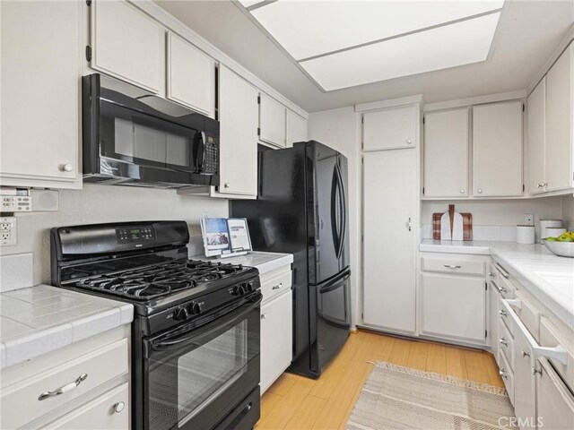 2563 Plaza Del Amo Unit 312, Torrance, CA 90503 - kitchen featuring black appliances, light wood-style flooring, white cabinets, and tile counters