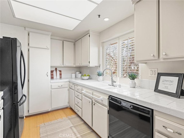 2563 Plaza Del Amo Unit 312, Torrance, CA 90503 - kitchen with black appliances, light wood-style floors, a sink, light countertops, and white cabinetry