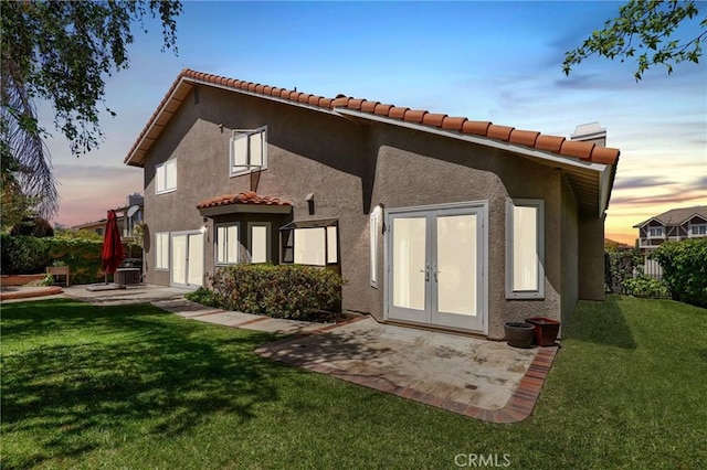 24092 Lapwing Ln, Laguna Niguel, CA 92677 - back of property at dusk with a tile roof, a patio, stucco siding, and central AC