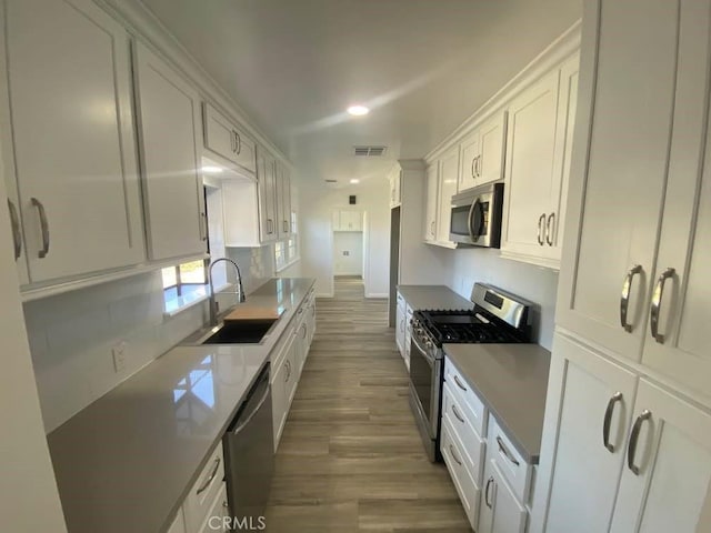 1515 Elizabeth St, Redlands, CA 92373 - kitchen with stainless steel appliances, a sink, wood finished floors, white cabinetry, and recessed lighting