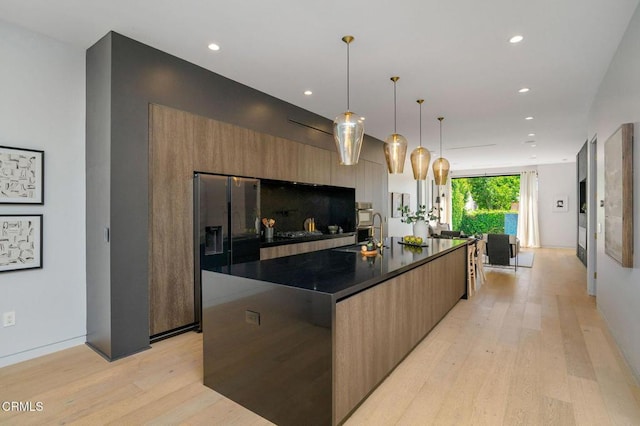 5622 Natick Ave, Sherman Oaks, CA 91411 - kitchen featuring modern cabinets, dark countertops, light wood-type flooring, a large island with sink, and recessed lighting