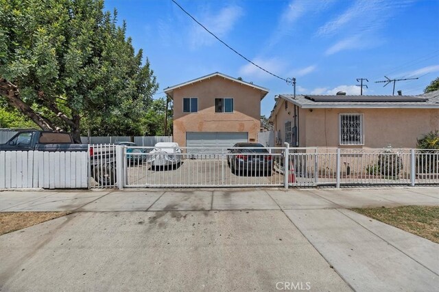 1218 S Sultana Ave Unit A, Ontario, CA 91761 - view of front of property featuring stucco siding, a gate, an attached garage, driveway, and solar panels