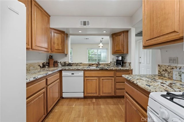 2916 Luciernaga St Unit A, Carlsbad, CA 92009 - kitchen with white appliances, a sink, light wood finished floors, brown cabinetry, and light stone counters