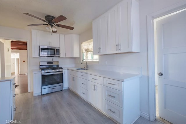 17196 Barbee St, Fontana, CA 92336 - kitchen with stainless steel appliances, a sink, a ceiling fan, white cabinets, and light wood-type flooring