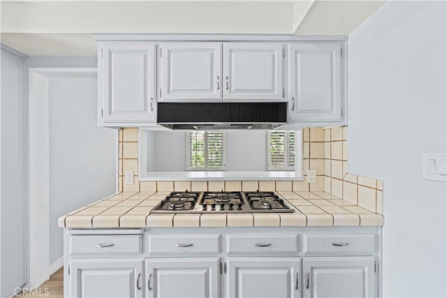 3316 Burritt Way, Glendale, CA 91214 - kitchen featuring tile counters, stainless steel gas stovetop, white cabinets, decorative backsplash, and range hood