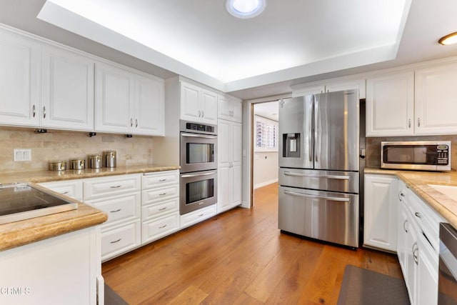 2210 Brambling Ln, Pasadena, CA 91107 - kitchen featuring appliances with stainless steel finishes, white cabinets, light wood-type flooring, and tasteful backsplash
