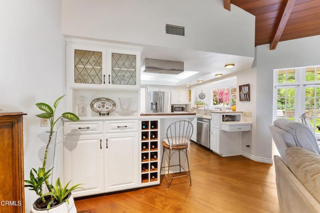 2210 Brambling Ln, Pasadena, CA 91107 - kitchen with stainless steel appliances, light wood finished floors, white cabinetry, light countertops, and a wooden ceiling with exposed beams