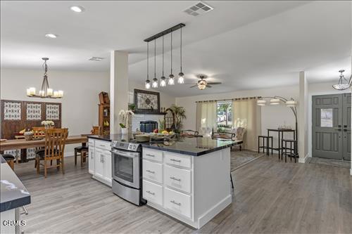 22150 Buena Vista St, Tehachapi, CA 93561 - kitchen featuring electric range, dark countertops, a chandelier, ceiling fan, and white cabinetry