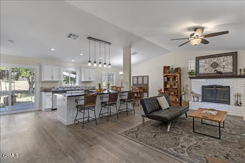 22150 Buena Vista St, Tehachapi, CA 93561 - living room with ceiling fan, wood finished floors, a brick fireplace, and vaulted ceiling