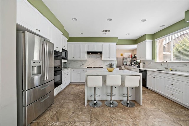 4127 Poplar Cir, Lake Elsinore, CA 92530 - kitchen with black appliances, white cabinets, decorative backsplash, a kitchen island, and recessed lighting