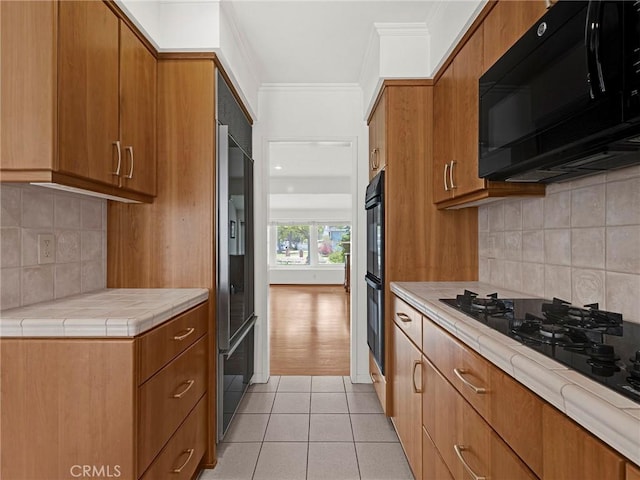 4854 Ranchito Ave, Sherman Oaks, CA 91423 - kitchen with black appliances, tile counters, ornamental molding, brown cabinets, and light tile patterned floors