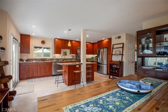 4 Amherst, Laguna Niguel, CA 92677 - kitchen with appliances with stainless steel finishes, a kitchen island, a kitchen breakfast bar, light tile patterned floors, and pendant lighting