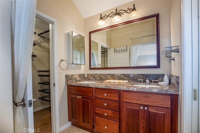 4 Amherst, Laguna Niguel, CA 92677 - bathroom featuring double vanity, a walk in closet, vaulted ceiling, and wood finished floors